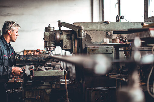 A machinist operating a metalworking lathe in a workshop