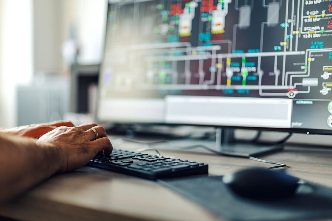 An operator at a keyboard monitoring a process-control dashboard